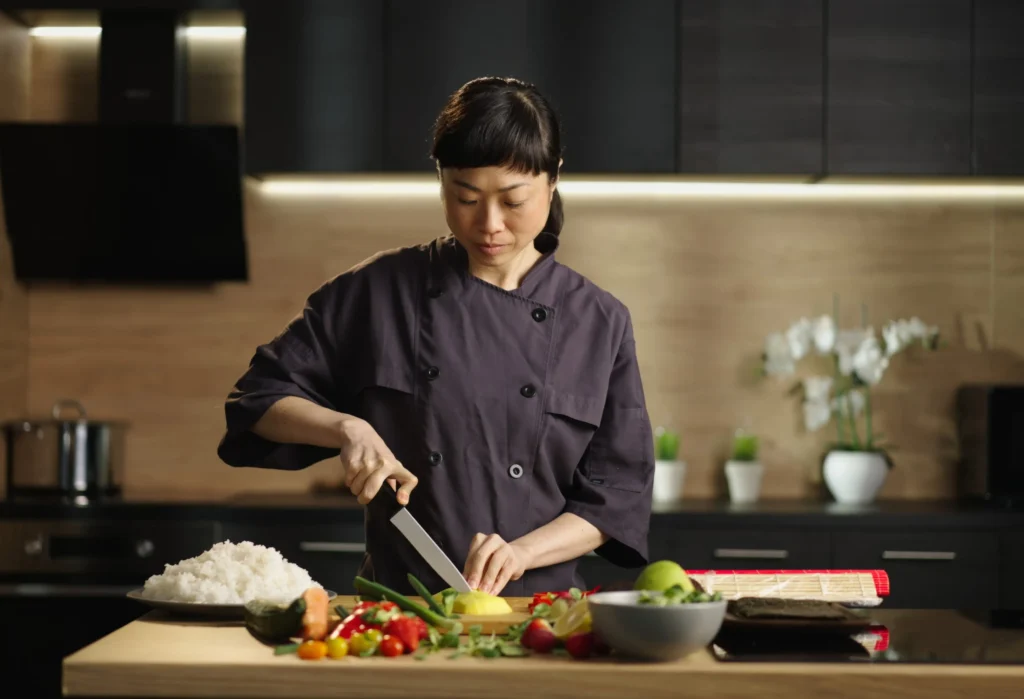 A private chef preparing fresh vegetables in a modern estate kitchen for a plant-based household.