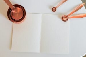 Open recipe notebook with copper measuring cups